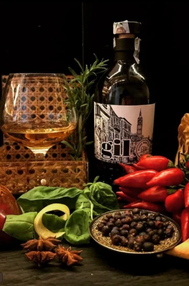 Bottiglia di gin con spezie aromatiche e bicchiere di liquore