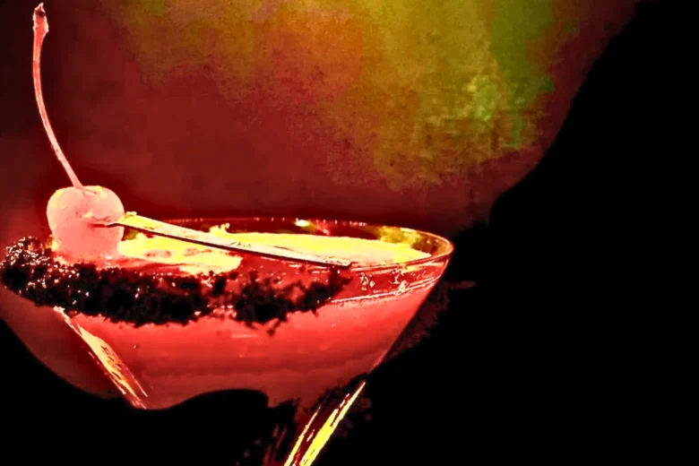 Cocktail rosso intenso servito in coppa, guarnito con ciliegia