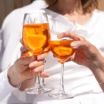 Tre donne brindano con calici di Spritz durante un aperitivo a Napoli