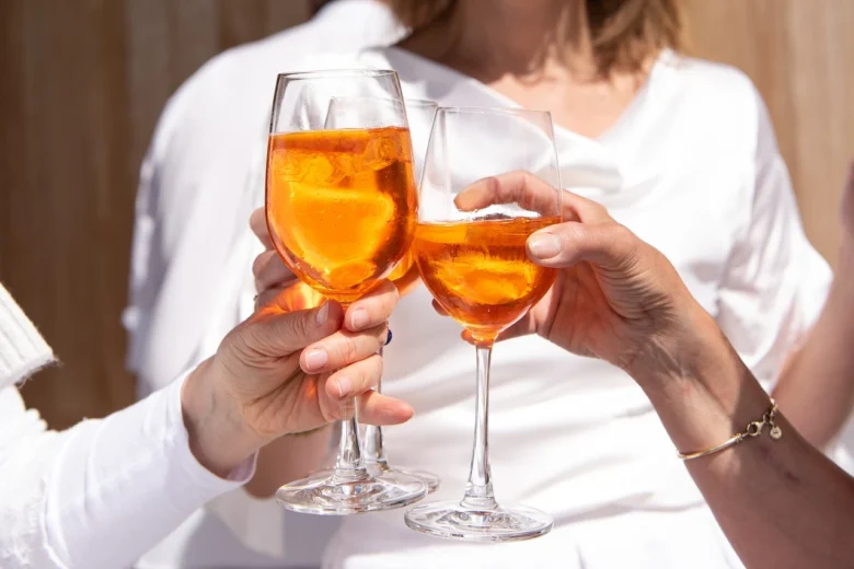 Tre donne brindano con calici di Spritz durante un aperitivo a Napoli