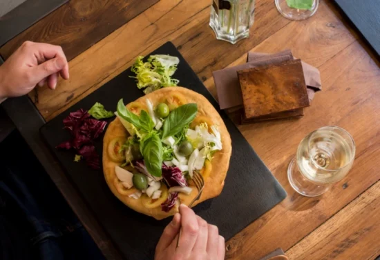Focaccia gourmet con insalata mista e olive servita al tavolo da KarmaCore