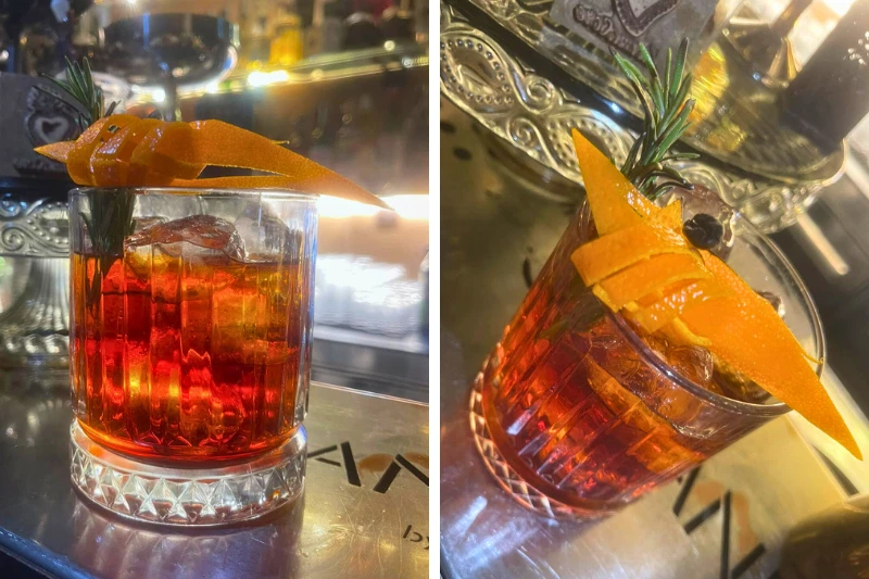 Negroni Sbagliato servito al bancone con scorza d’arancia e rosmarino