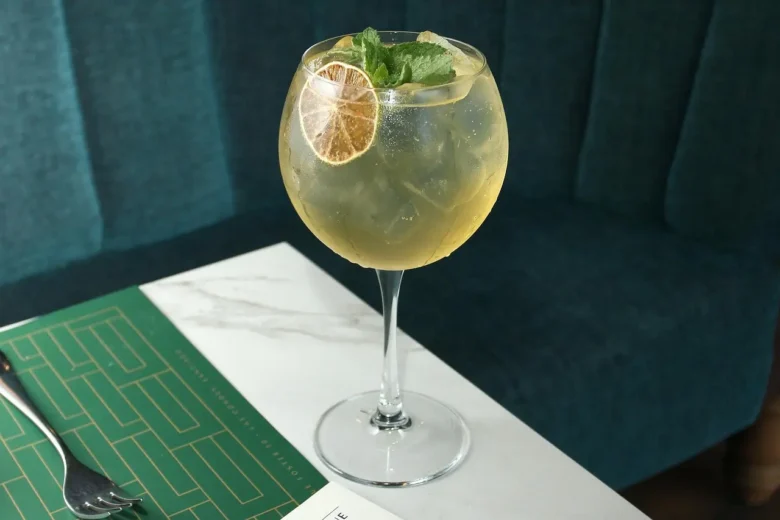 Cocktail con gin servito in calice balloon, guarnito con menta e fetta di lime